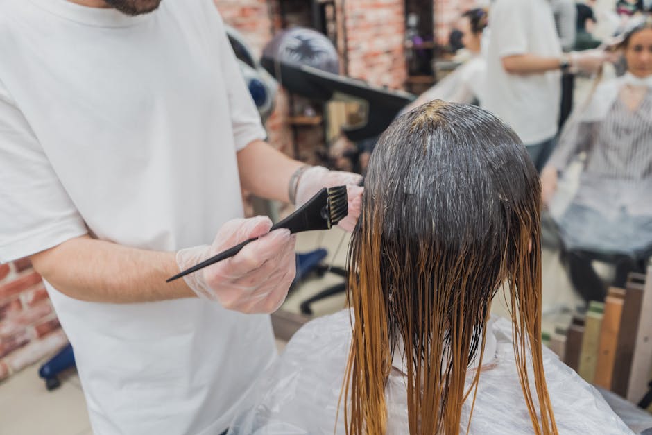 Hair coloring process in a salon, showcasing stylist applying color to client's hair